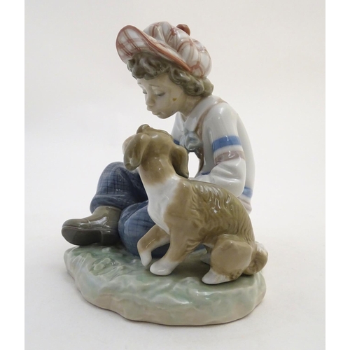 85 - A Lladro figure of a boy with a dog pulling flower petals, I Hope She Does, model no. 5450. Marked u... 