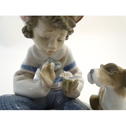 85 - A Lladro figure of a boy with a dog pulling flower petals, I Hope She Does, model no. 5450. Marked u... 