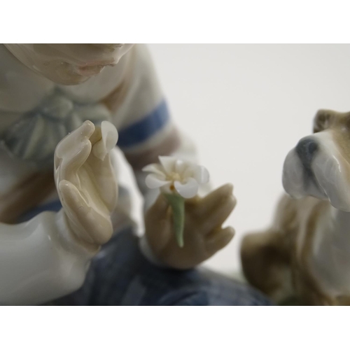 85 - A Lladro figure of a boy with a dog pulling flower petals, I Hope She Does, model no. 5450. Marked u... 