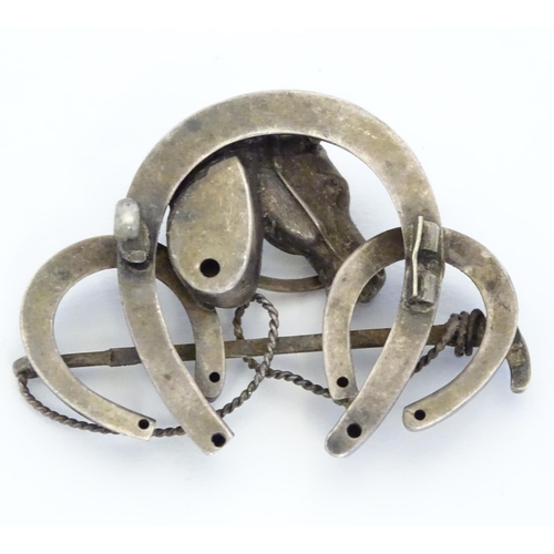 226 - A white metal brooch front. Formed as three horseshoes with horse head and riding crop decoration 1 ... 