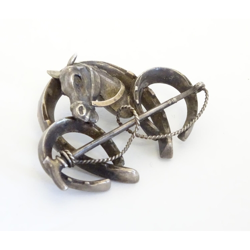226 - A white metal brooch front. Formed as three horseshoes with horse head and riding crop decoration 1 ... 