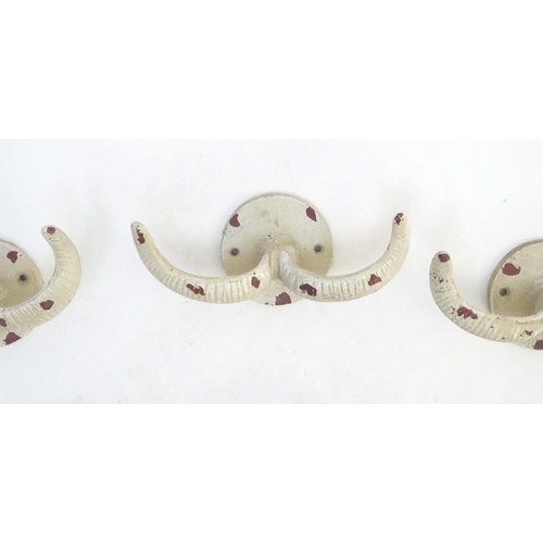 293 - Five cast wall hanging coat hooks formed as stylised rams horns with painted decoration. Approx. 7 3... 