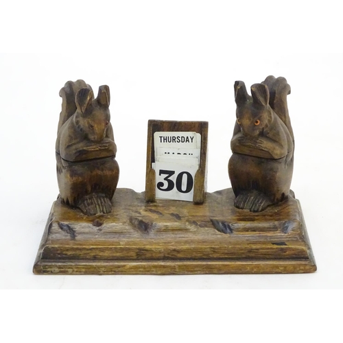 298 - A carved wooden desk calendar and standish / inkwell, the inkwells formed as squirrels eating nuts. ... 