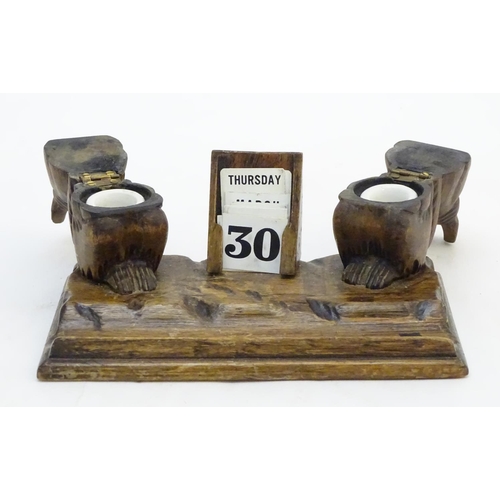 298 - A carved wooden desk calendar and standish / inkwell, the inkwells formed as squirrels eating nuts. ... 