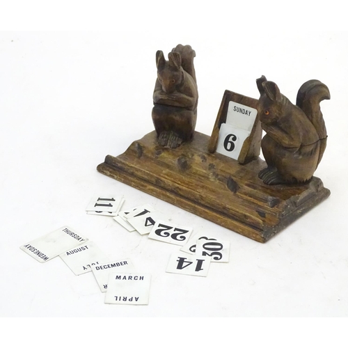298 - A carved wooden desk calendar and standish / inkwell, the inkwells formed as squirrels eating nuts. ... 