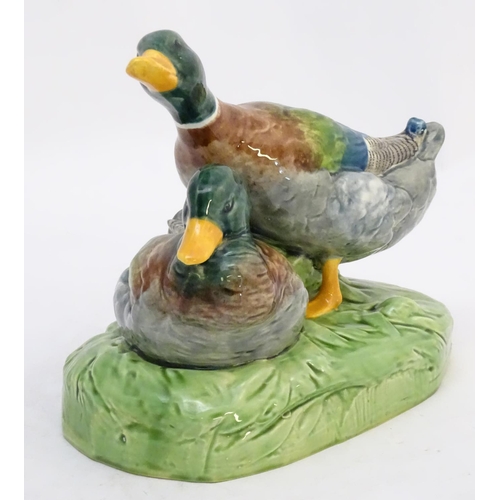 306 - A large ceramic model formed as two ducks on an oval base, one sitting, one standing. Impressed 1264... 