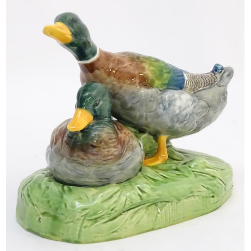306 - A large ceramic model formed as two ducks on an oval base, one sitting, one standing. Impressed 1264... 