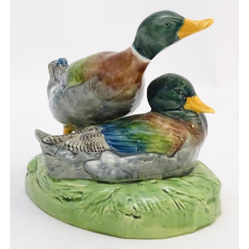 306 - A large ceramic model formed as two ducks on an oval base, one sitting, one standing. Impressed 1264... 