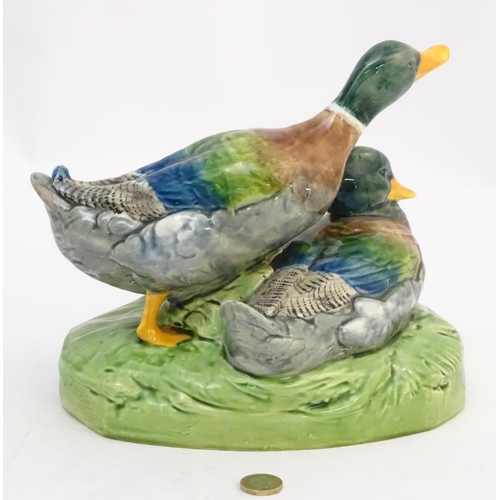 306 - A large ceramic model formed as two ducks on an oval base, one sitting, one standing. Impressed 1264... 