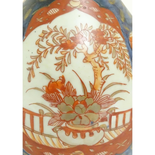 1 - An Oriental double gourd vase in the Imari palette with lobed panels depicting plants on a terrace, ... 