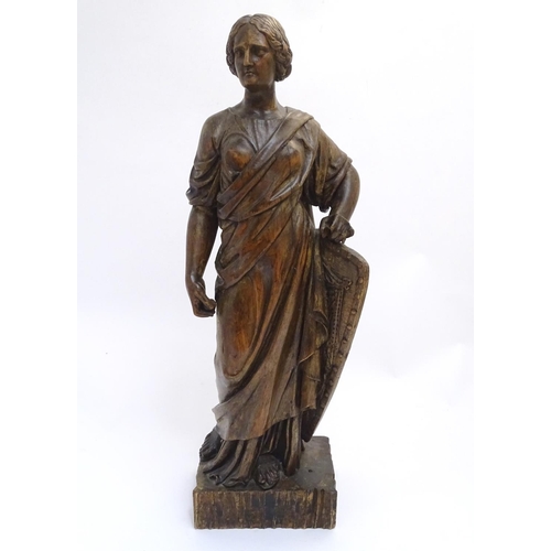 1030 - An 18th-19thC carved walnut statuette, depicting a classical female with shield, standing 34