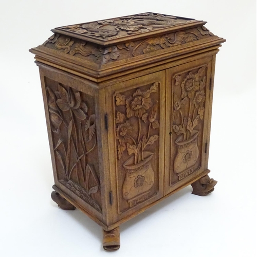 1032 - A 19thC Chinese hardwood table cabinet, with carved foliate and floral decoration, the lid with depi... 