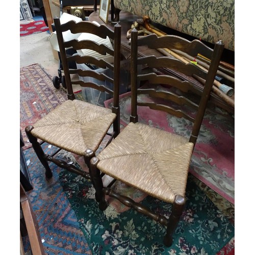 213 - A pair of 20thC rush seated ladder back dining chairs. Each approx. 37