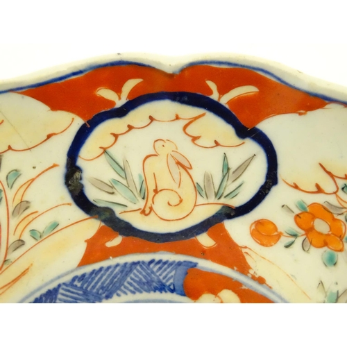 29 - An Imari style plate with a lobed rim, decorated with floral and foliate scenes with panelled depict... 