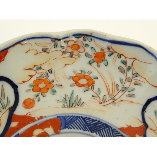 29 - An Imari style plate with a lobed rim, decorated with floral and foliate scenes with panelled depict... 