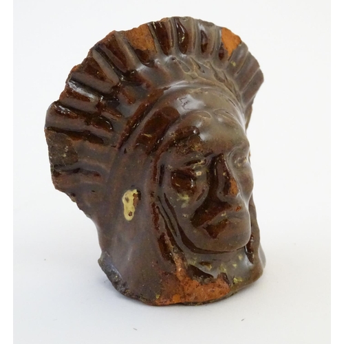 64 - A 19thC treacle and slip glazed terracotta window stop formed as the bust of Native American Indian ... 