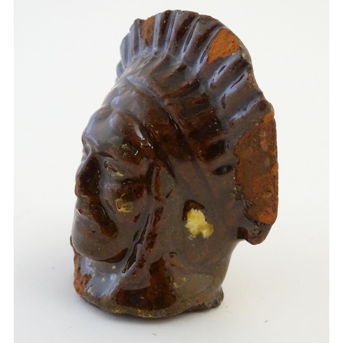 64 - A 19thC treacle and slip glazed terracotta window stop formed as the bust of Native American Indian ... 