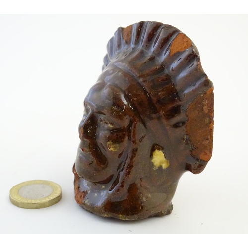 64 - A 19thC treacle and slip glazed terracotta window stop formed as the bust of Native American Indian ... 