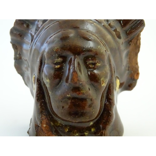 64 - A 19thC treacle and slip glazed terracotta window stop formed as the bust of Native American Indian ... 