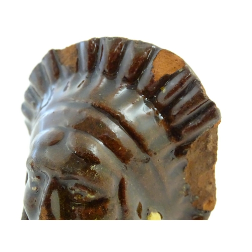 64 - A 19thC treacle and slip glazed terracotta window stop formed as the bust of Native American Indian ... 