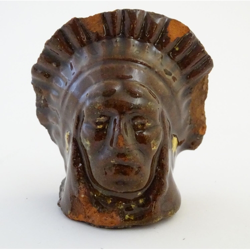 64 - A 19thC treacle and slip glazed terracotta window stop formed as the bust of Native American Indian ... 