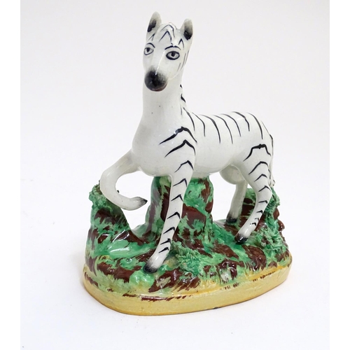 69 - A Staffordshire figure modelled as a zebra on a naturalistic oval base. Approx. 4 3/4