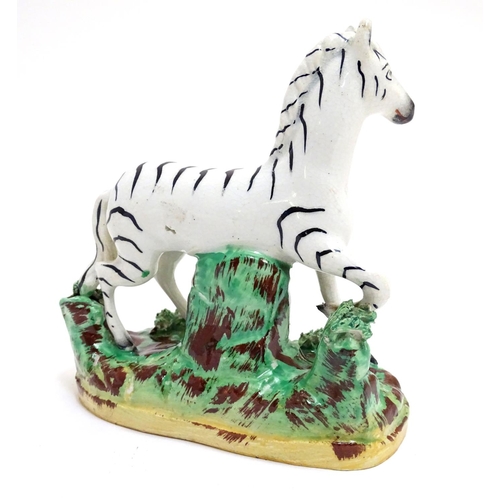 69 - A Staffordshire figure modelled as a zebra on a naturalistic oval base. Approx. 4 3/4