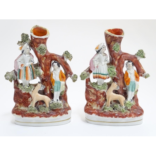 71 - A pair of Staffordshire figural spill vases with a man and woman resting on the branches of a tree w... 