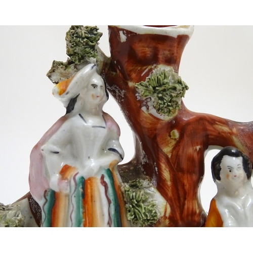 71 - A pair of Staffordshire figural spill vases with a man and woman resting on the branches of a tree w... 