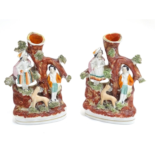 71 - A pair of Staffordshire figural spill vases with a man and woman resting on the branches of a tree w... 