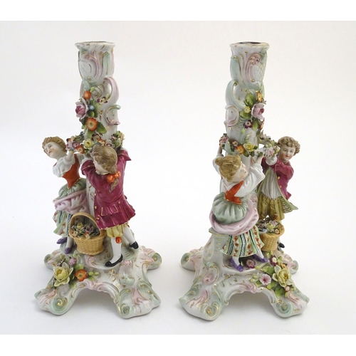 73 - A pair of 19thC German figural lamp bases with two figures arranging flowers, raised on a scrolling ... 