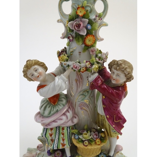 73 - A pair of 19thC German figural lamp bases with two figures arranging flowers, raised on a scrolling ... 