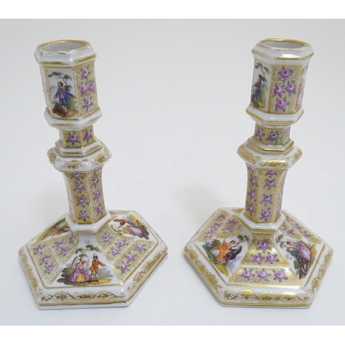 80 - A pair of Berlin porcelain candlesticks on hexagonal bases with gilt and floral detail and hand pain... 