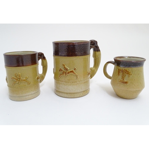 92 - Three Denby two tone stoneware tankards / mugs, two with relief hunting scenes and handles formed as... 