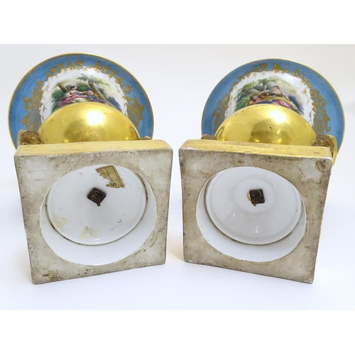 134 - A pair of hand painted twin handled campagna urns, each decorated with a young seated couple on a bl... 