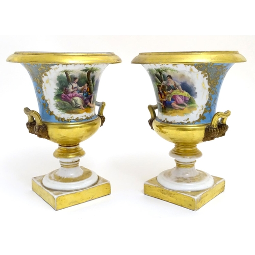 134 - A pair of hand painted twin handled campagna urns, each decorated with a young seated couple on a bl... 