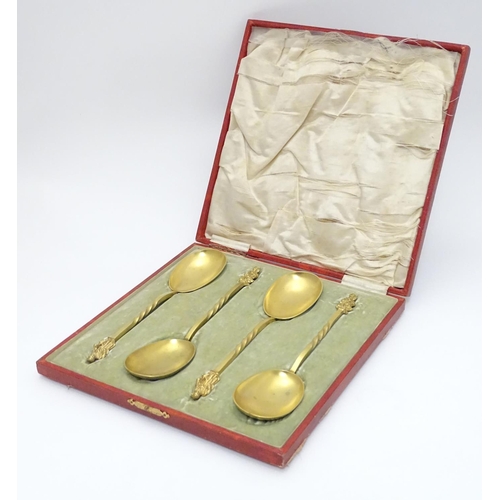 429 - A cased set of four gilded serving spoons surmounted by a religious figure. Each approx. 8