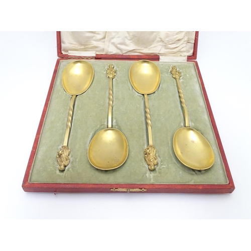 429 - A cased set of four gilded serving spoons surmounted by a religious figure. Each approx. 8