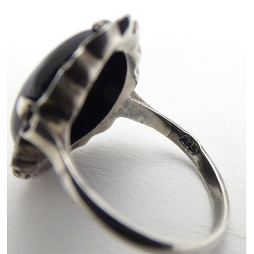 461 - A silver ring set with black onyx cabochon  bordered by marcasites. Ring approx size O.