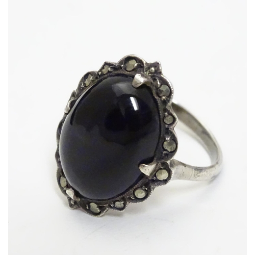 461 - A silver ring set with black onyx cabochon  bordered by marcasites. Ring approx size O.