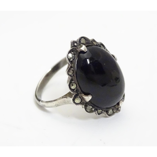 461 - A silver ring set with black onyx cabochon  bordered by marcasites. Ring approx size O.