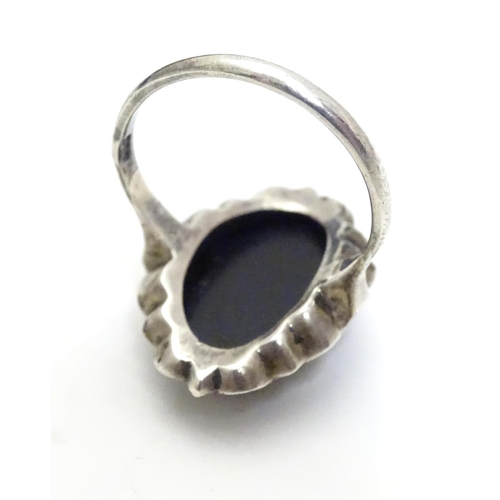 461 - A silver ring set with black onyx cabochon  bordered by marcasites. Ring approx size O.