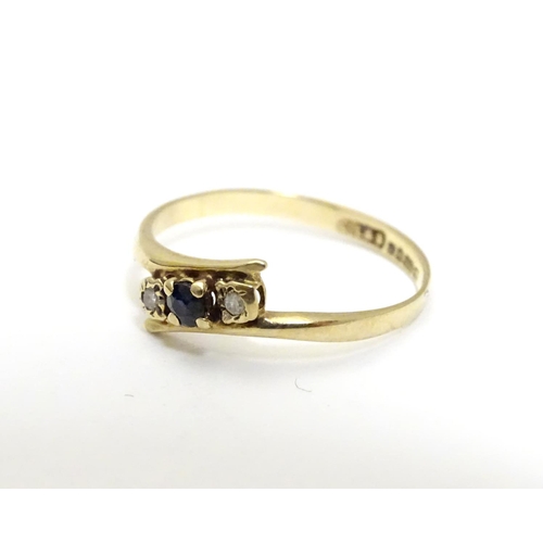 463 - A 9ct gold ring set with central spinel flanked by two white stones. Ring size approx J 1/2