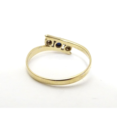 463 - A 9ct gold ring set with central spinel flanked by two white stones. Ring size approx J 1/2