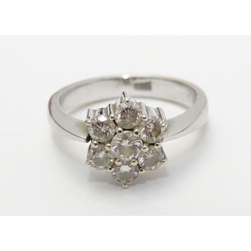 464 - An 18ct gold ring set with 7 diamonds in a daisy cluster setting. the setting approx 3/8