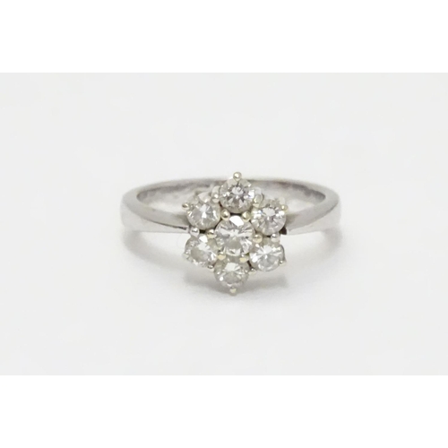 464 - An 18ct gold ring set with 7 diamonds in a daisy cluster setting. the setting approx 3/8