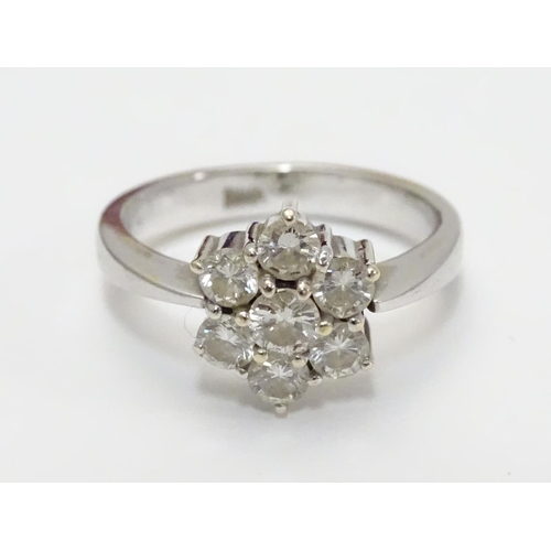 464 - An 18ct gold ring set with 7 diamonds in a daisy cluster setting. the setting approx 3/8