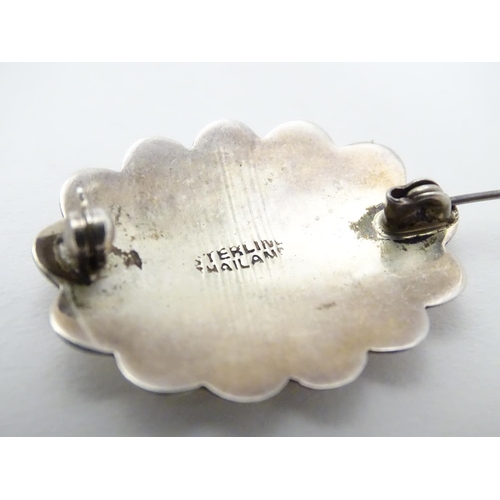 504 - A silver brooch of scalloped oval form with engraved decoration, marked Sterling Thailand. 1 1/4