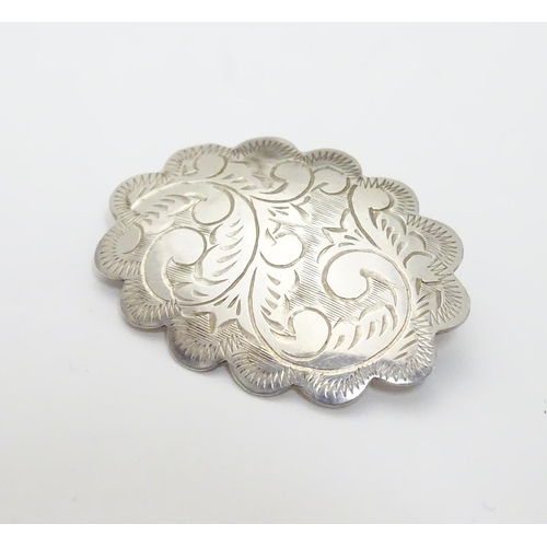 504 - A silver brooch of scalloped oval form with engraved decoration, marked Sterling Thailand. 1 1/4