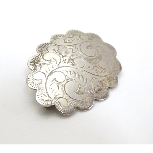 504 - A silver brooch of scalloped oval form with engraved decoration, marked Sterling Thailand. 1 1/4